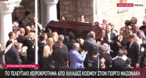 Στη Νίκαια, στην παλιά του γειτονιά αναπαύεται εδώ και λίγη ώρα ο Γιώργος Μαζωνάκης μετά την Εξόδιο Ακολουθία με τη σορό να βγαίνει από τον Ιερό Ναό Αγίας Τριάδος και να χειροκροτείται από πλήθος κόσμου.